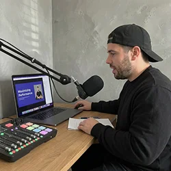 Creator in a backwards cap at a home podcast desk